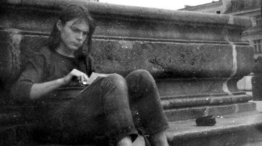 Matthias Domaschk sitzt auf einem Bordstein am Marktplatz Jena. Er blättert durch mehrere Zettel, die er sich auf den Schoß gelegt hat.