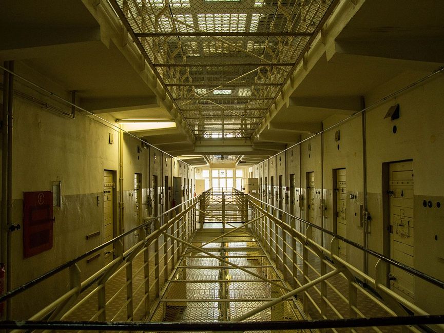 Blick ins Obergeschoss. Die in der Mitte befindlichen Freiräume zwischen den einzelnen Geschossen sind mit Gittern gesichert. Links und rechts erkennt man die Zellentüren.