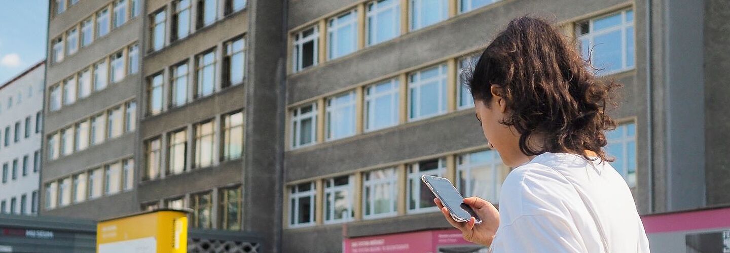 Eine Schülerin steht mit einem Smartphone in der Hand im Innenhof der 'Stasi-Zentrale. Campus für Demokratie'.