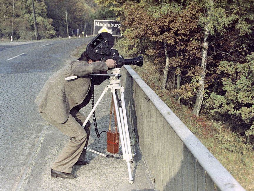 Ein Stasi-Mitarbeiter mit Kamera observiert von einer Brücke aus Fahrzeuge auf der Autobahnstrecke Nähe Magdeburg.