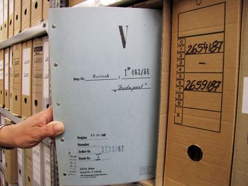 Ein Aktenband mit Stasi-Unterlagen wird aus einem Karton entnommen