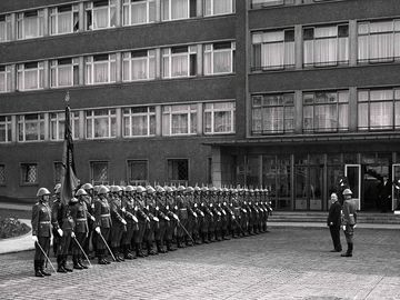 Historisches Foto einer Reihe von Soldaten in Uniformen vor Haus 1. Vor diesen steht Erich Mielke
