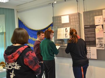 Vier junge Menschen sehen sich Objekte in einer Ausstellung an.
