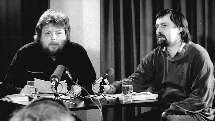 An einem Tisch mit Mikrofonen sitzen Lutz Rathenow (links) und Jürgen Fuchs (rechts).