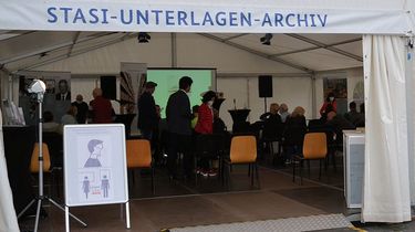 Festzelt für die EinheitsEXPO 2021 in Halle mit der Aufschrift 'Stasi-Unterlagen-Archiv'. Im Innern befinden sich stehende und sitzende Besucherinnen und Besucher