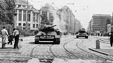 Demonstranten werfen Steine auf sowjetische Panzer.