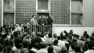 Besetzung der Frankfurter Bezirksverwaltung dr Staatssicherheit am 5. Dezmeber 1989. Eine Mneschenmenge steht vor einem Gebäude. Einer spricht gerade durch ein Megafon.