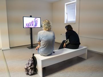 Zwei Besucherinnen sitzen vor einer Videoinstallation bei der 12. Berlin Biennale.