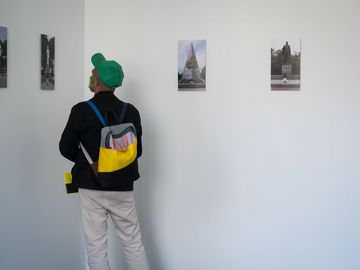 Ein Besucher der 12. Berlin Biennale schaut sich Fotos an, die an einer Wand befestigt sind.