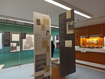 Blick in eine Ausstellung, die im Rahmen der EinheitsEXPO im Stasi-Unterlagen-Archiv Halle gezeigt wurde. Zu sehen sind Ausstellungstafeln mit Texten, historischen Fotos und Karikaturen.