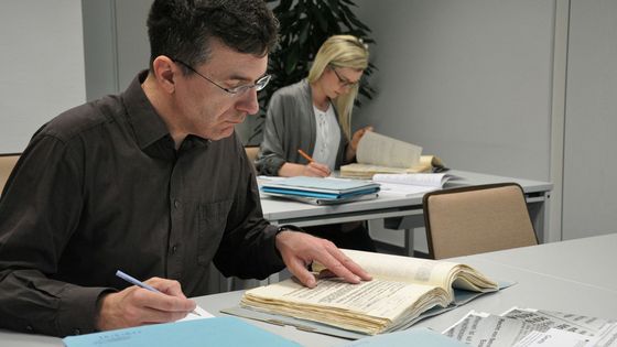 Eine Frau und ein Mann nehmen im Lesesaal des Stasi-Unterlagen-Archivs Einsicht in Stasi-Akten.