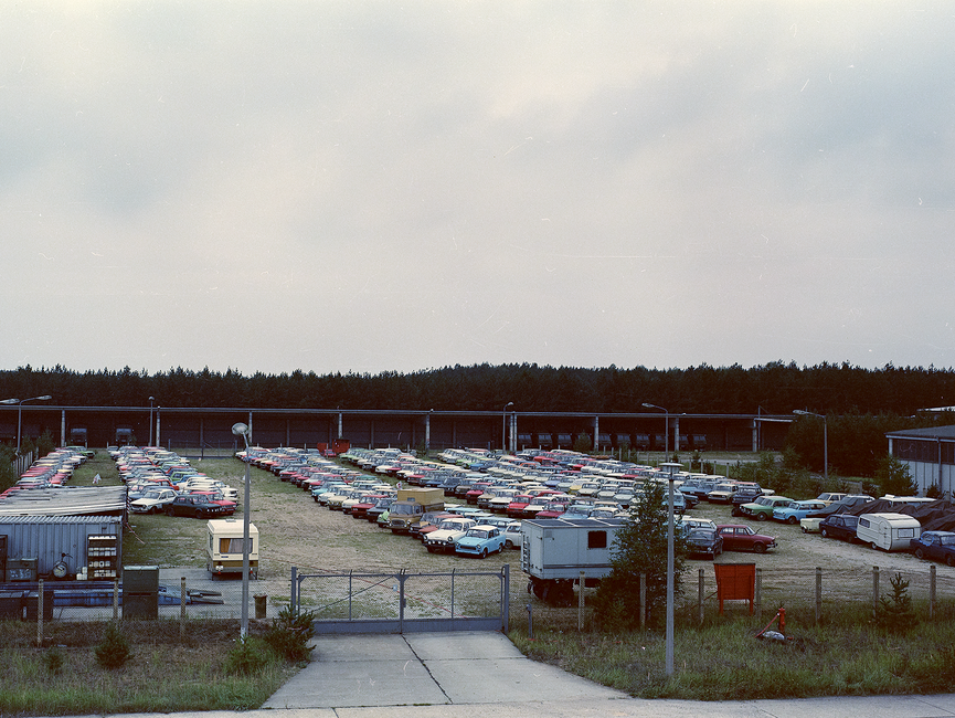 Das Bild zeigt einen großen Platz, der fast vollständig it in Reihe aufgestellten Autos gefüllt ist.