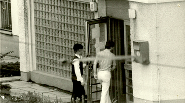 Zwei Männer betreten nacheinander ein Gebäude mit der Hausnummer 26.