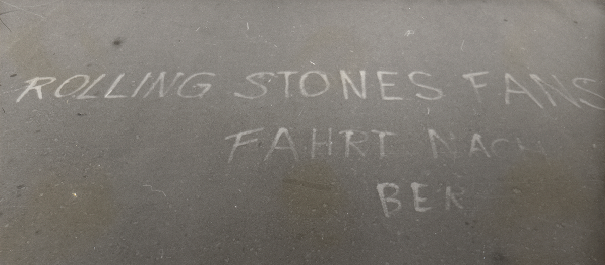 Schwarzweiß Aufnahme von der Fahrbahn mit der Aufschrift: "Rolling Stones Fans fahrt nach Ber"