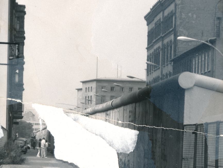 Auf dem schwarz-weiß Lichtbild ist der Blick auf die Berliner Mauer von der Westseite der Stadt dokumentiert. Die mit Grafitti versehenen Mauerelemente werden im Bildvordergrund von einem Metallgitterzaun abgelöst. Das Foto war mehrfach zerrissen worden und konnte nur anteilig manuell rekonstruiert werden.