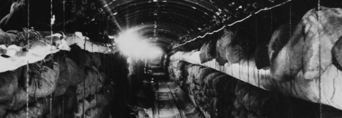 Im Hochkantformat wurde in den langen Tunnel mit der gewölbten Decke hinein fotografiert. Auf beiden Seiten sind Regale voller Leinensäcke.
