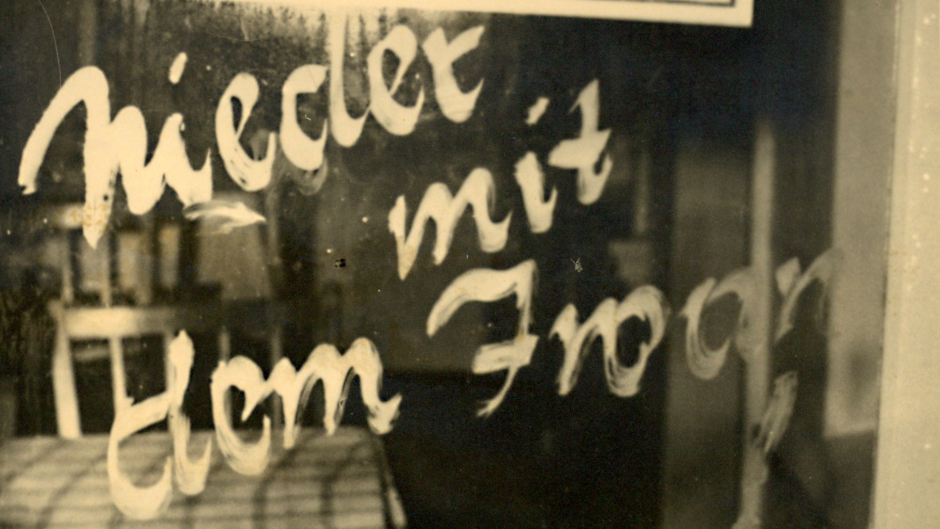 Eine Losung mit dem Schriftzug 'Nieder mit dem Iwan' auf einer in der Tür verbauten Fensterscheibe.